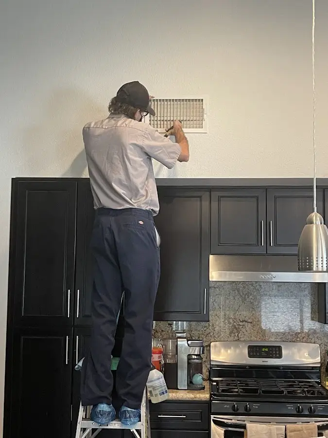 Technician inspecting an air vent during HVAC service in Portage